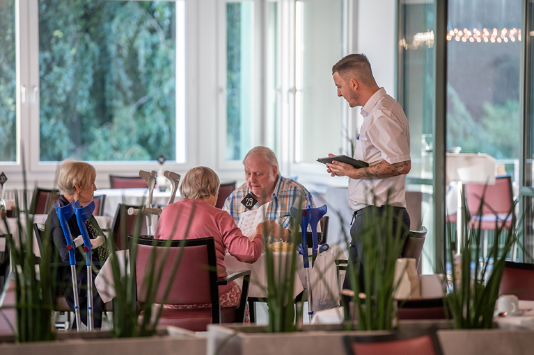 Geriatrische Rehabilitationspatienten bestellen beim Hotellerie Mitarbeiter im Tannzapfe Restaurant